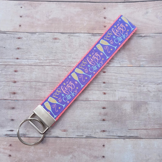 Pop, fizz, clink champagne glasses on pink webbing keychain 6"